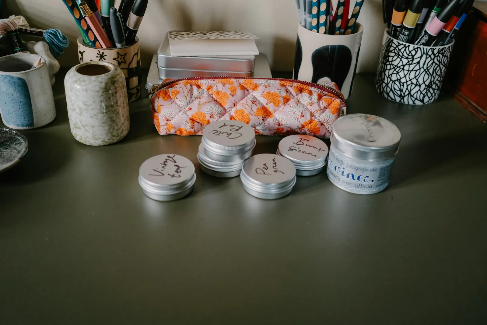 Escritorio ordenado con latas, estuche y portalápices