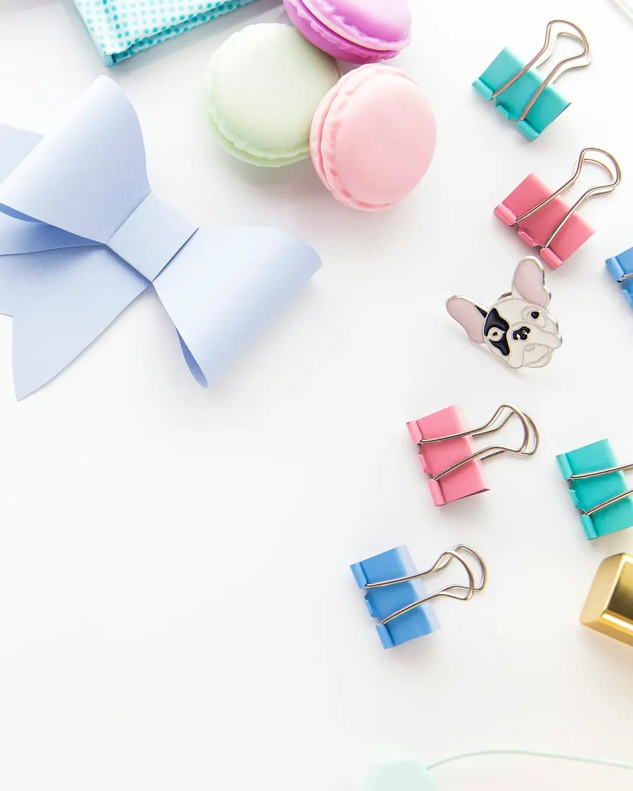 Escritorio pastel con lazo de papel, clips de colores y macarons